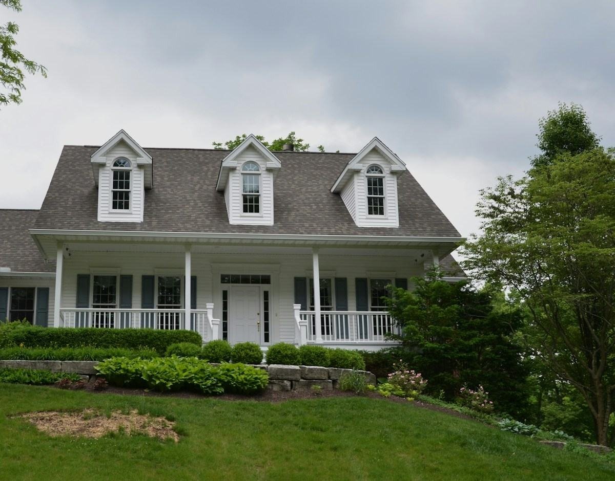 A white house with three dormers and a gray shingle roof