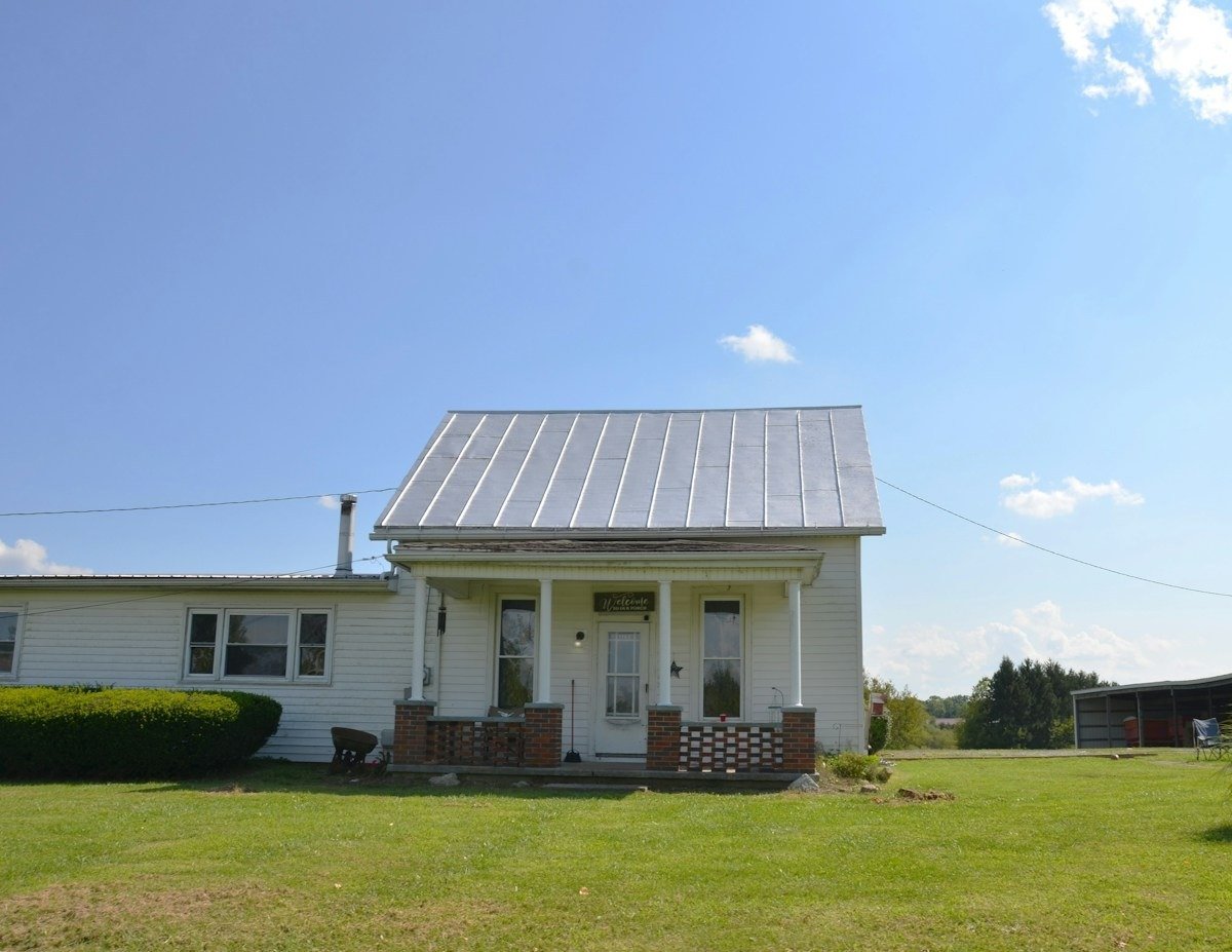 A white house with a silver standing-seam metal roof